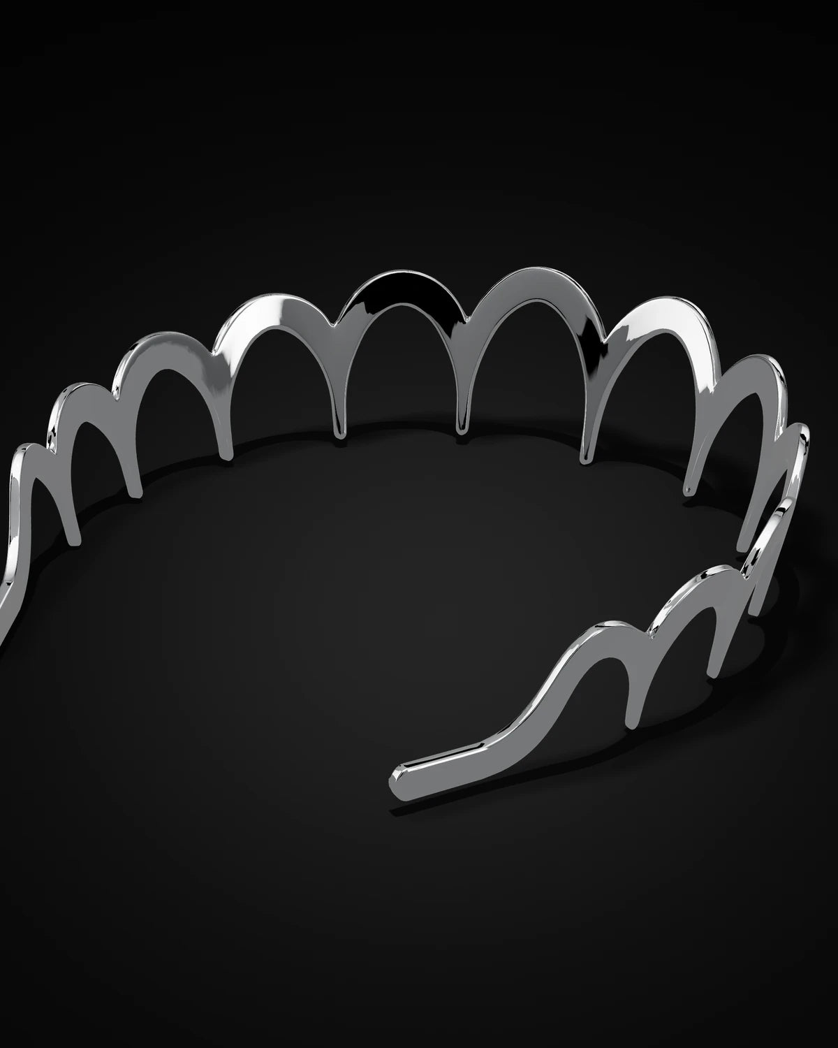 The polished steel Zig Zag Hairband resting on a black surface, seen from above at an angle